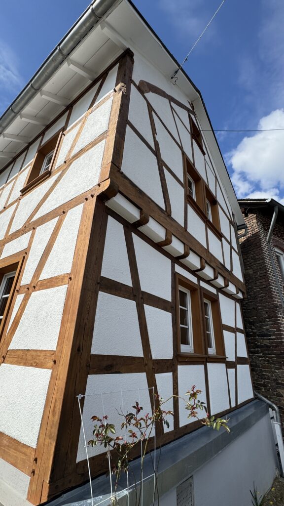 Fachwerkfassade mit sichtbaren Holzbalken und weißen Gefachen